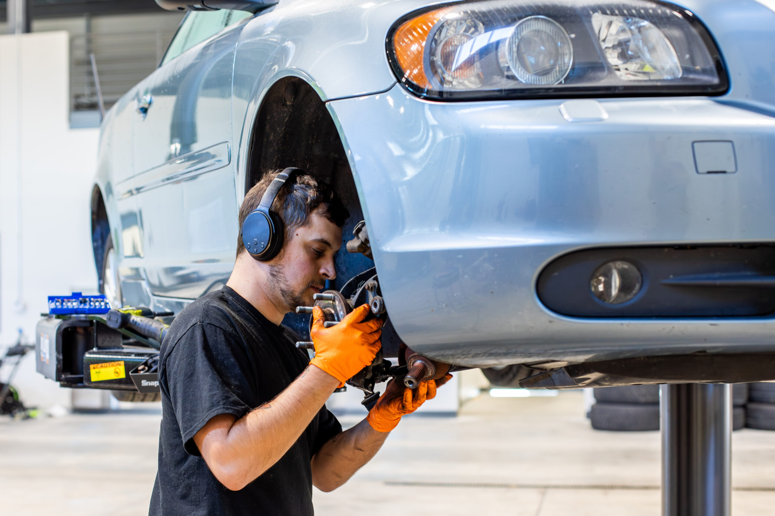 Mechanic inspecting a vehicle’s brakes during routine preventive maintenance on a lift.