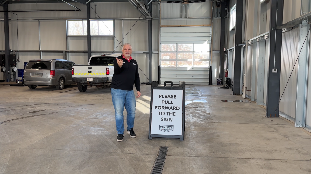 Van Wyk Auto technician welcoming a customer inside the indoor service lane in Sheboygan.