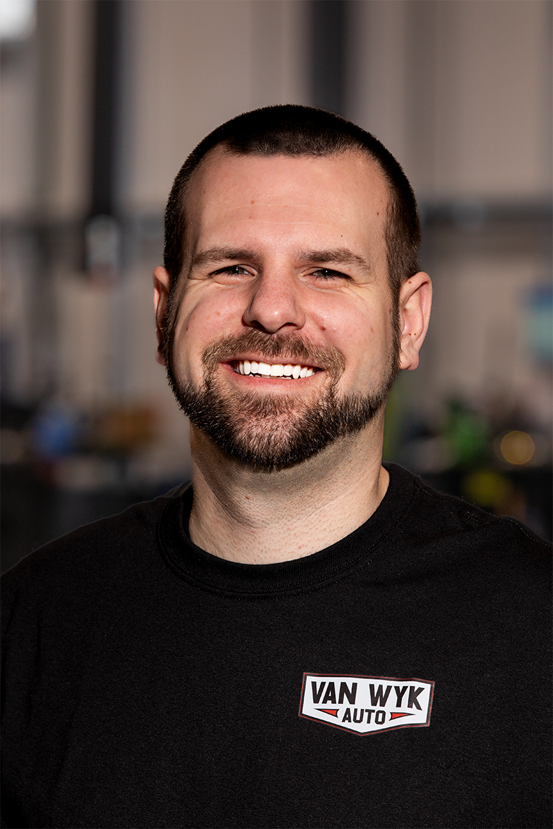 Headshot of Andy, a porter at Van Wyk Auto, smiling inside the shop
